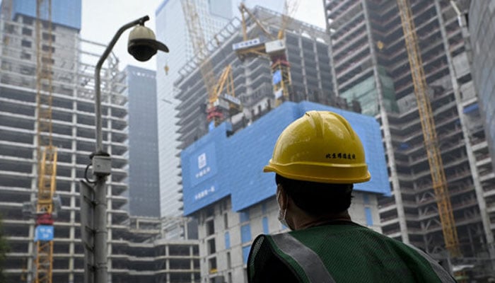 A worker walks past a construction site in Beijing. — AFP/File