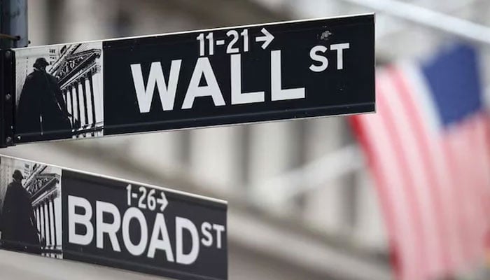 A Wall Street sign hangs in front of a US Flag outside the New York Stock Exchange (NYSE) before the Federal Reserve announcement in New York City, US on September 18, 2024.— Reuters