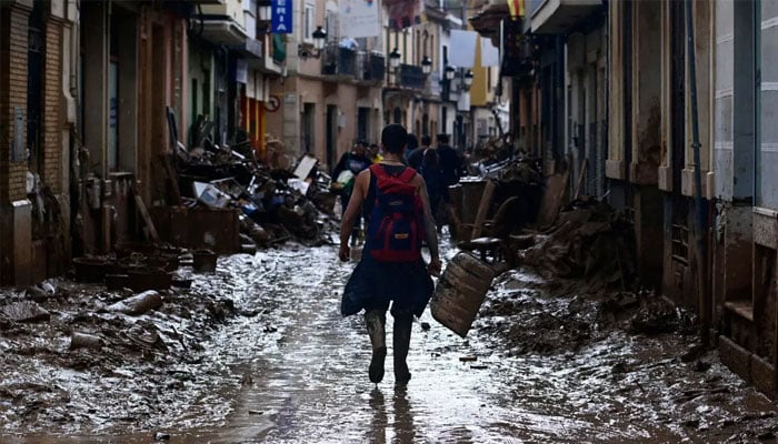 A volunteer walks on a muddy street as he leaves Paiporta, in the region of Valencia, eastern Spain, on November 3, 2024, in the aftermath of devastating deadly floods. — AFP