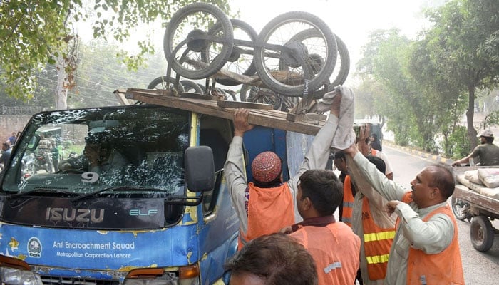 Workers of Anti Encroachment Squad of Metropolitan Corporation loading pushcarts on a loading truck during illegal Encroachment operation at Impress road in Lahore on October 2, 2023. — Online