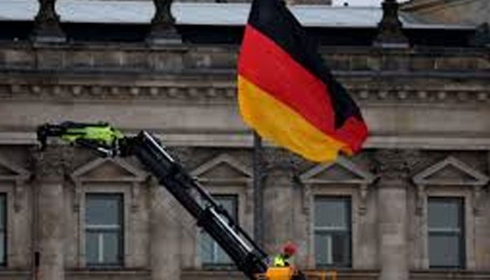 A German national flag flutters in front of Reichstag building as a man works on a crane in Berlin, Germany on May 21, 2024.— Reuters