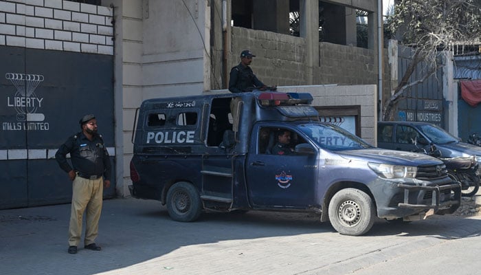 Police personnel stand guard outside a factory where two Chinese nationals were allegedly shot, in Karachi on November 5, 2024. — AFP