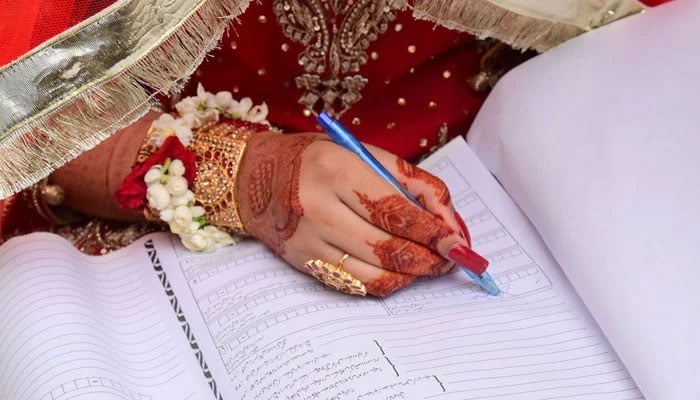 A representational image showing a bride signing Nikah papers. — X@iris_petal_dew/File