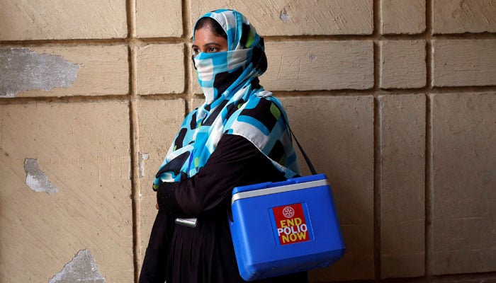 A vaccinator with kit box, waits for her colleagues, to do an anti-polio campaign in a low-income neighbourhood in Karachi on April 9, 2018. — Reuters