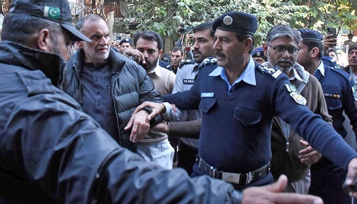 Police personnel escort PTI leader (centre) Azam Khan Swati during his court hearing in controversial tweets case. — Online