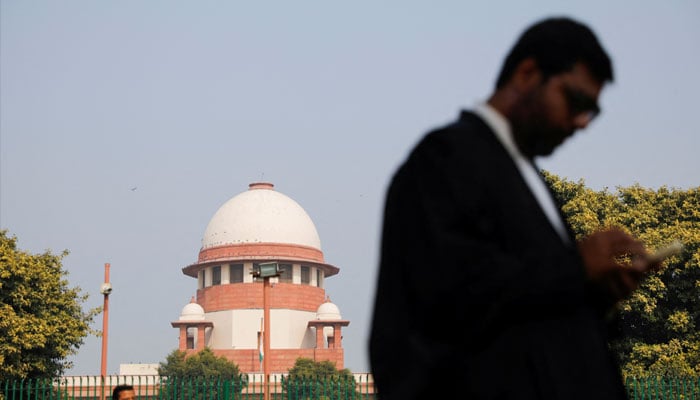 A lawyer looks into his mobile phone in front Indias Supreme Court in New Delhi, December 11, 2023. — Reuters