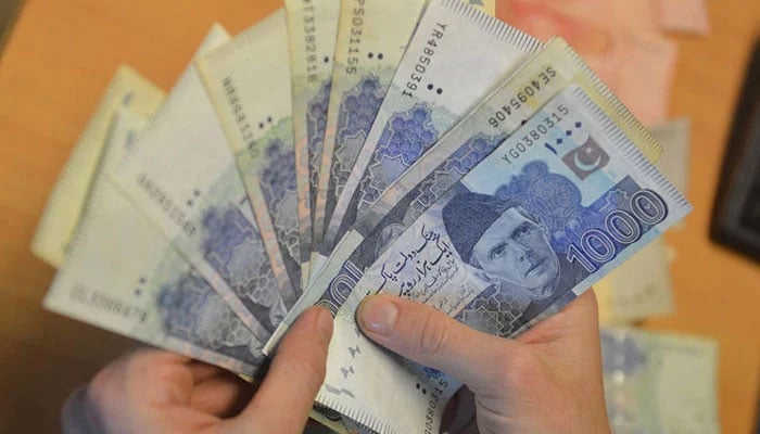 A money changer counts Pakistans currency at a market in Karachi. — AFP/File