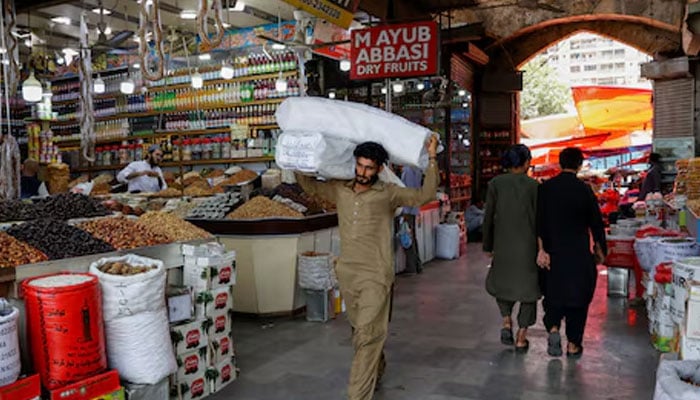 A man walks with sacks of supplies on his shoulder to deliver to a nearby shop at a market in Karachi on Pakistan June 11, 2024. — Reuters