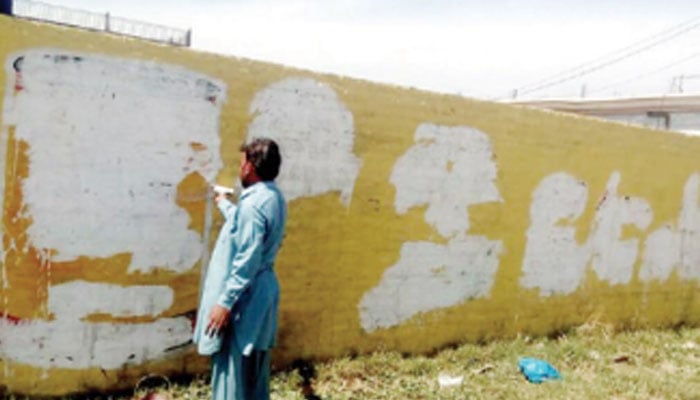 In this image, a labourer removes chalking from a wall. — APP/File