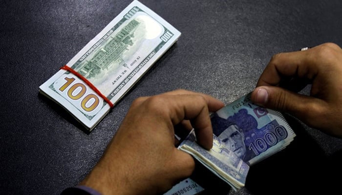 A currency trader counts Pakistani Rupee notes as he prepares an exchange of US dollars. — Reuters/File