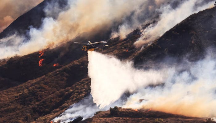 An helicopter makes a drop as smoke billows from the Mountain Fire in Santa Paula, California, US, November 7, 2024. — Reuters