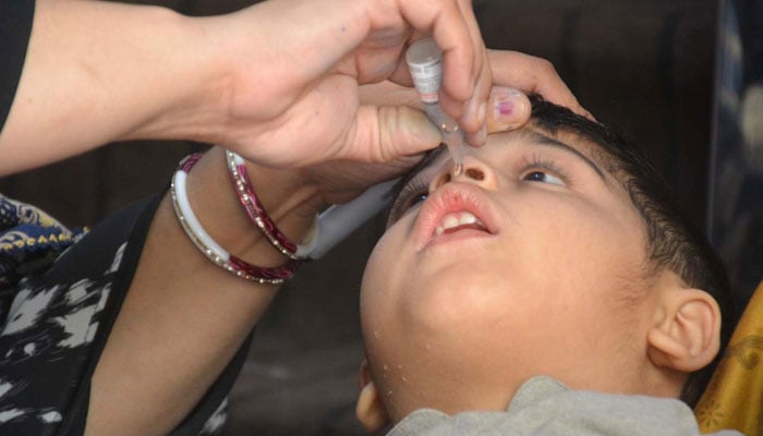 Polio worker administering polio drops to a child during anti-polio vaccination campaign. — INP/file