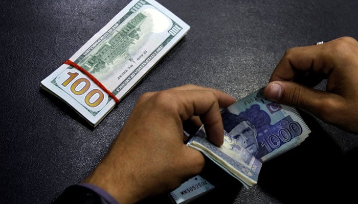 A currency trader counts Pakistani Rupee notes as he prepares an exchange of US dollars in Islamabad. — Reuters/File