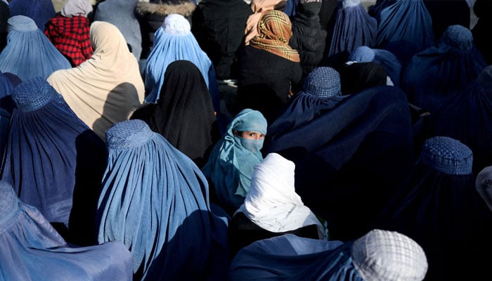 A girl sits in front of a bakery in the crowd with Afghan women waiting to receive bread in Kabul, Afghanistan, January 31, 2022. — Reuters