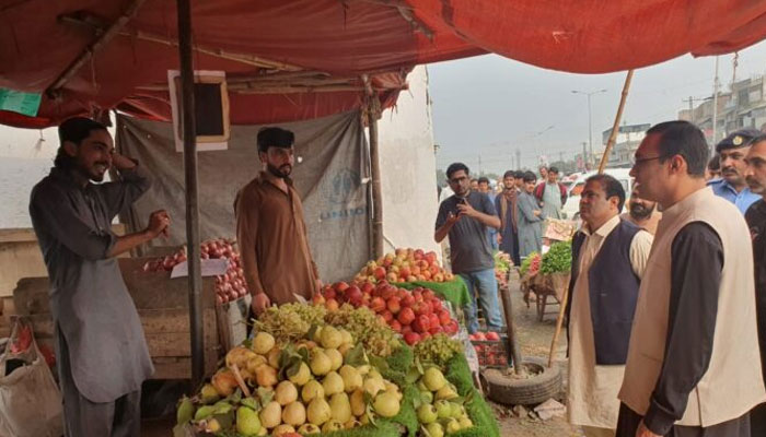 Islamabad Capital Territory (ICT) administration officials talking to owner of a fruit stall. — APP/File