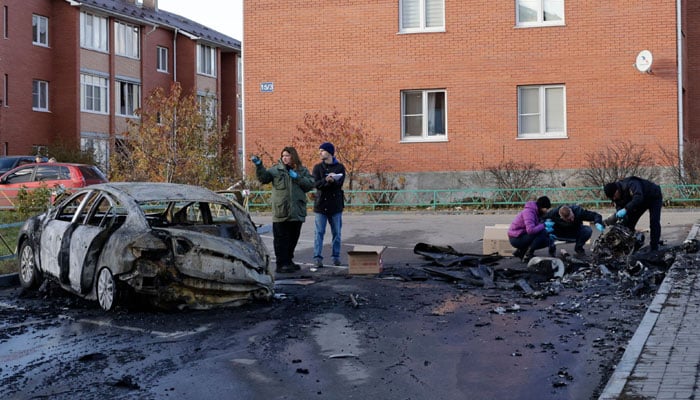 Russian law enforcement officers inspect the wreckage of a drone next to a burnt-out car in the courtyard of residential buildings following a drone attack in the village of Sofyino, Moscow region, on November 10, 2024. — AFP