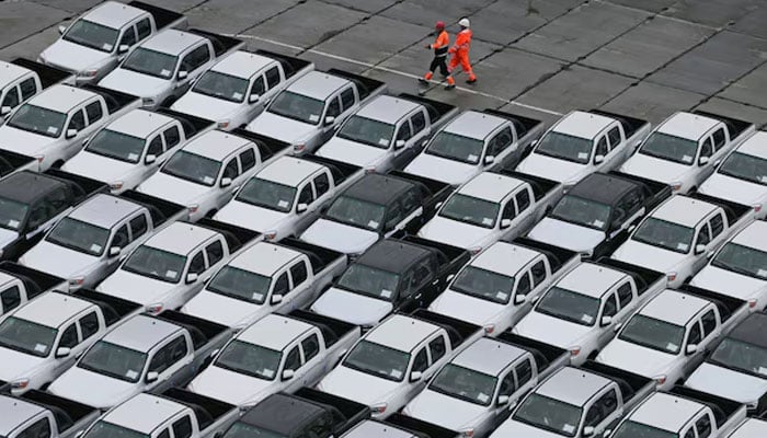 Workers walk past new cars. — Reuters/File