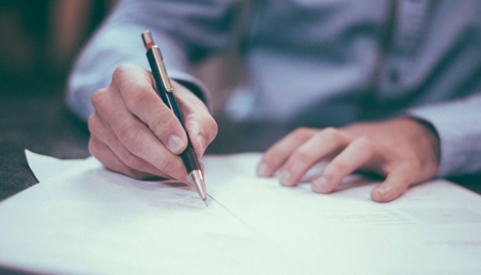 A representational image showing a person signing a document. — Unsplash/File