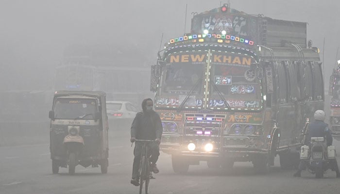 Commuters ride along a road engulfed in thick smog in Lahore on November 11, 2024. — AFP