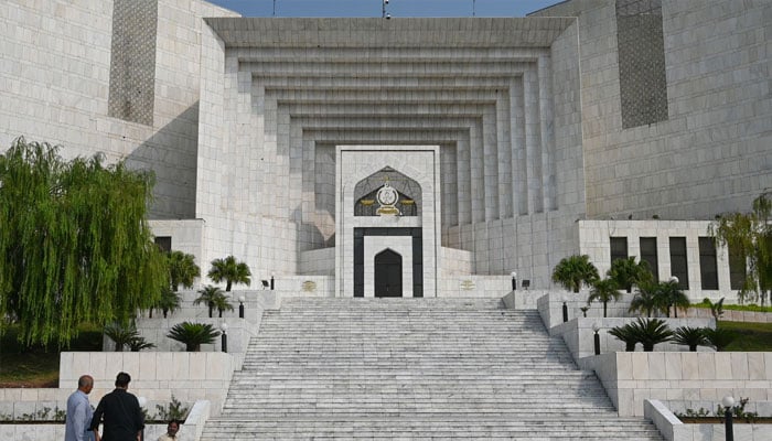 In this photograph taken on October 23, 2024, workers stand in front of the Pakistan´s Supreme Court building in Islamabad. — AFP