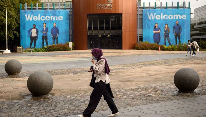 A woman wearing a face mask walks through University Square past Coventry University’s Alan Berry Building at the beginning of the new academic year, at Coventry University, in Coventry, central England on September 23, 2020. — AFP