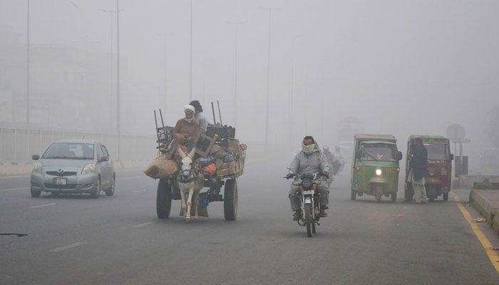 Vehicles navigate in thick smog layer , as air quality is very poor and visibility remains low in the early hours in Multan on November 8, 2024. — APP/File