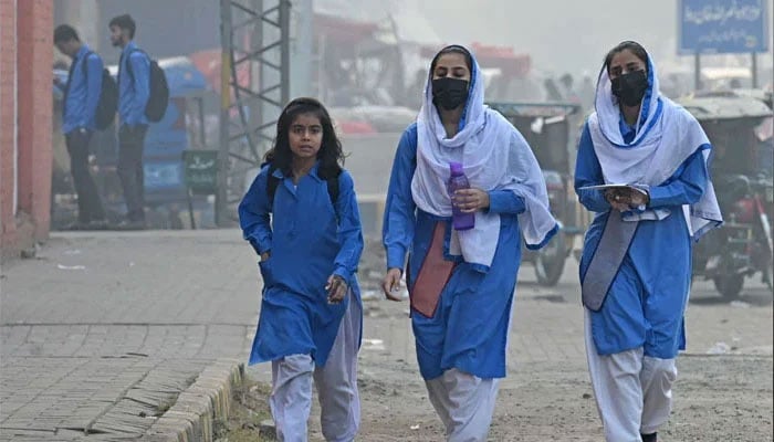 Students wearing face masks walk along a street amid smoggy conditions in Lahore. — AFP/File