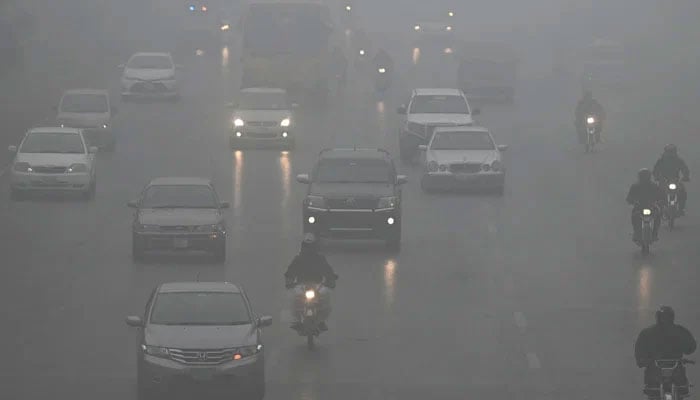 Commuters make their way along a road amid dense smog in Islamabad on January 22, 2024. — AFP