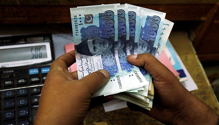 A trader counts Pakistani rupee notes at a currency exchange booth in Peshawar, Pakistan on December 3, 2018. — Reuters