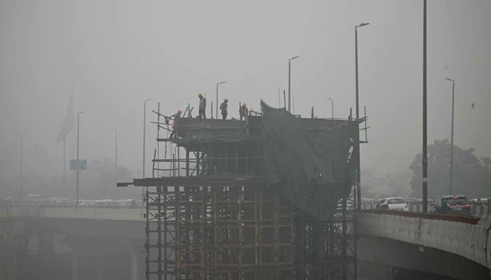 Labourers stand on a scaffolding amid dense smog in New Delhi on November 13, 2024. — AFP