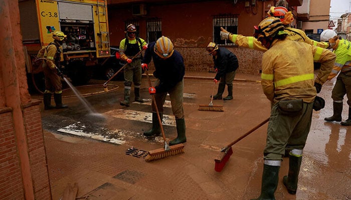 Firefighters clean a drainage system blocked by mud following catastrophic flooding, as Spain braces for torrential rain in Paiporta, Valencia on November 13, 2024. — Reuters