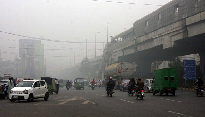 Commuters drive along a road engulfed in smog at Qartaba Chowk in Lahore on November 14, 2024. — PPI