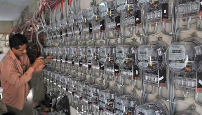 A technician fixes new electricity meters at a residential building in Karachi, Pakistan, on May 13, 2010. — AFP