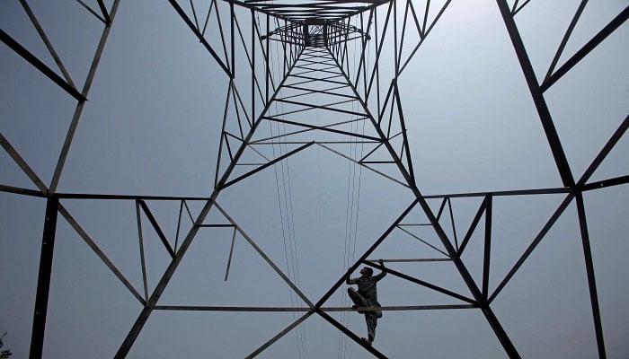 A worker of Peshawar Electric Supply Company (PESCO) climbs up a high-voltage pylon in Peshawar, Pakistan August 7, 2017. —Reuters