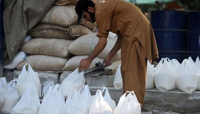 A person can be seen putting sugar in a plastic shopping bag while packing. — AFP/File