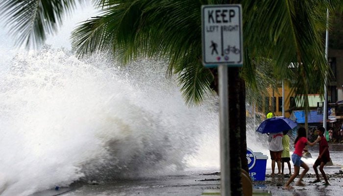 People react as large waves break along a seawall ahead of the expected landfall of Super Typhoon Man-yi, in Legaspi City, Albay province on November 16, 2024. — AFP