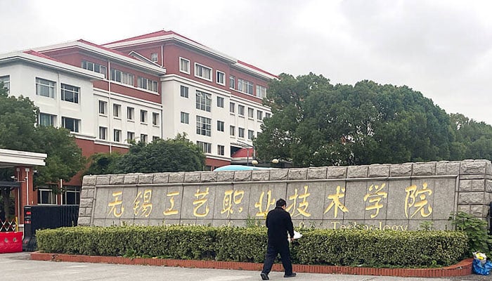 A man lays a bouquet of flowers at the entrance to the Wuxi Vocational College of Arts and Technology following a knife attack at the school in Wuxi, China. — Reuters/file