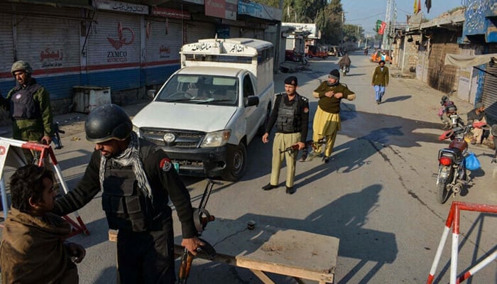 Police stand guard along a road they blocked after militants seized a police station in Bannu on December 19, 2022. — AFP