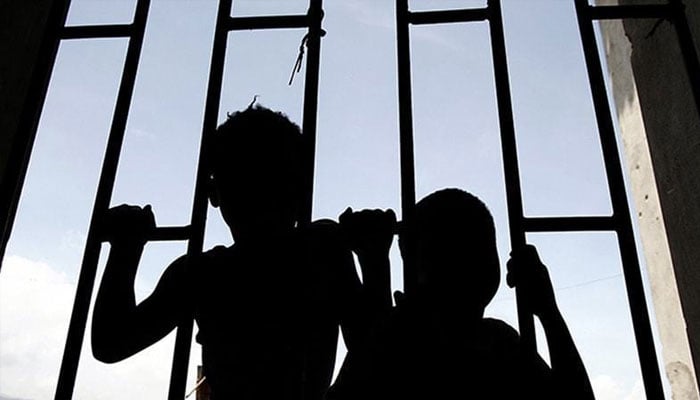 Silhouette of two children seen behind a grill. —Reuters/File