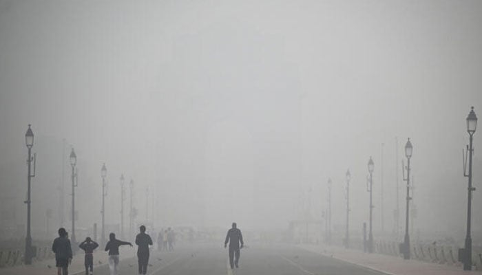 Pedestrians walk along the Kartavya Path engulfed in thick smog, near India Gate in New Delhi on November 18, 2024. — AFP