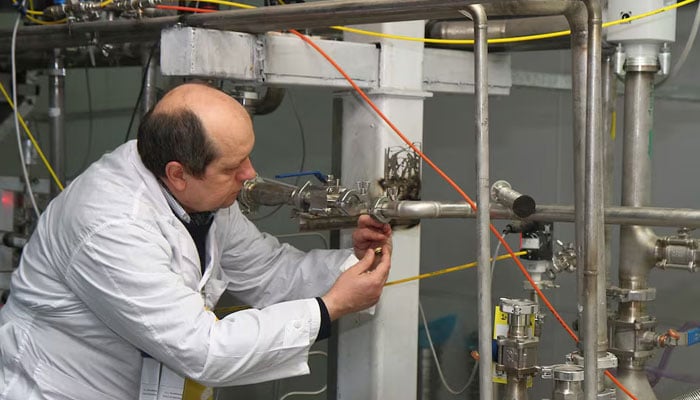 An unidentified International Atomic Energy Agency inspector disconnects the connections between the twin cascades for 20 percent uranium production at nuclear power plant of Natanz, south of Tehran, Iran, on Jan. 20, 2014. — AFP