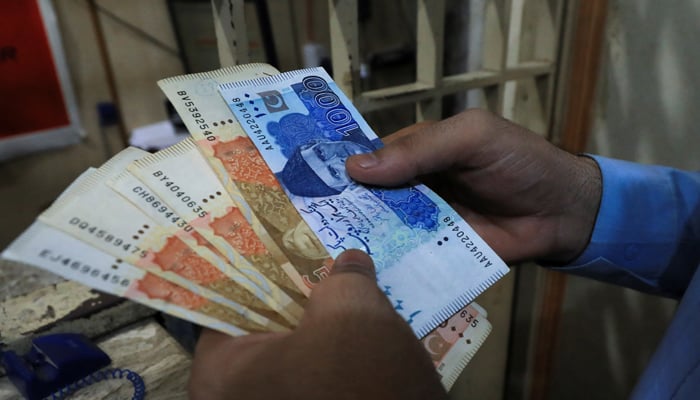 A man counts Pakistani rupee notes at a currency exchange shop in Peshawar, on September 12, 2023. — Reuters