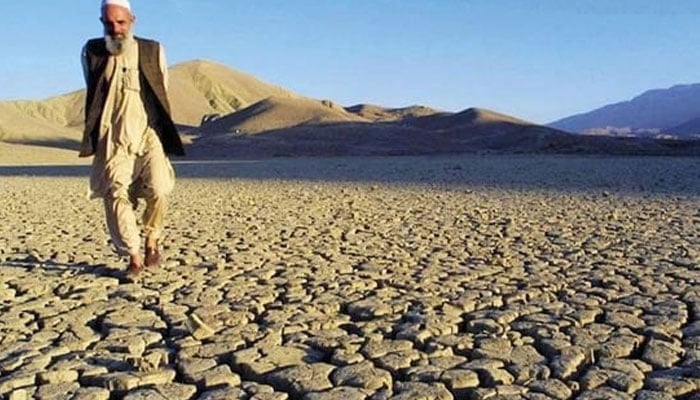 The representational image shows a man walking on the dried, cracked landscape. — AFP/File