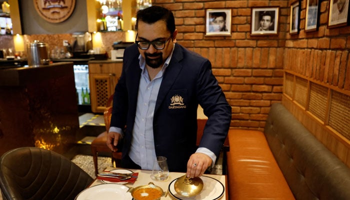 A manager of a restaurant shows a freshly prepared butter chicken dish and Dal Makhani inside a restaurant at a mall. — Reuters/file