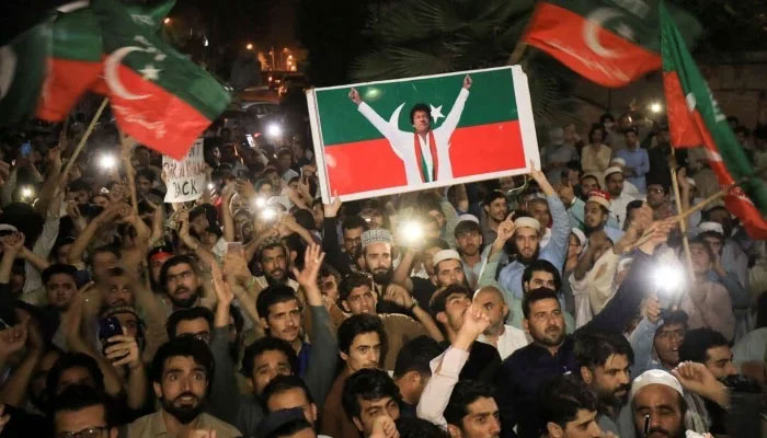 Supporters of PTI wave flags and chant in support of former prime minister Imran Khan during a rally in Peshawar on April 10, 2022. — Reuters