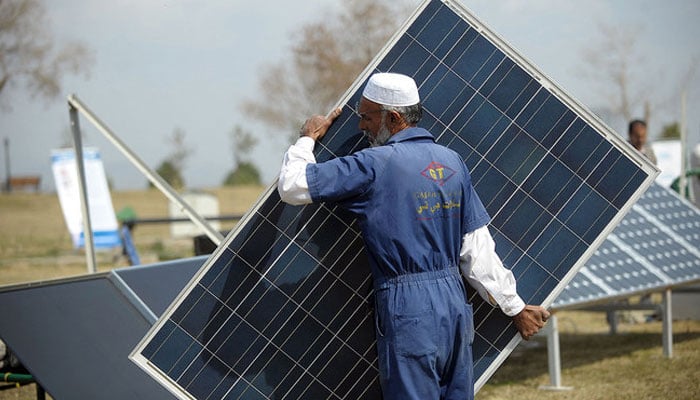 An employee arranges a solar panel during a marketing demonstration in a park in Islamabad. — AFP/File