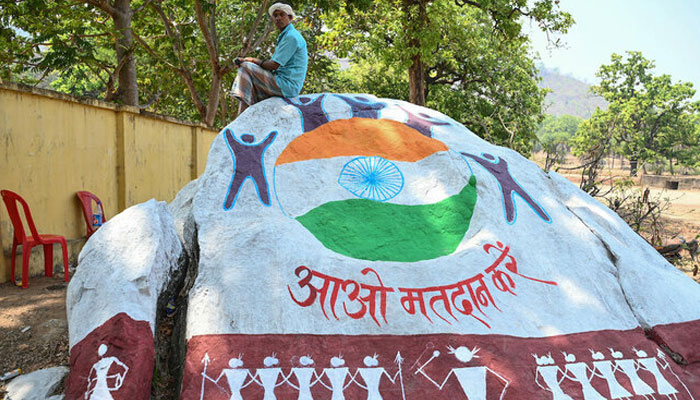 A resident sits on a boulder painted with voter awareness mural in Dugeli village of Chhattisgarh state, one of the last strongholds of the Naxal rebels, on April 19, 2024. — AFP