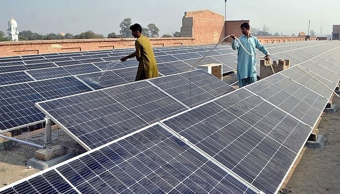 Workers washing 300 KWP solar PV system in Multan, on December 4, 2022. — APP