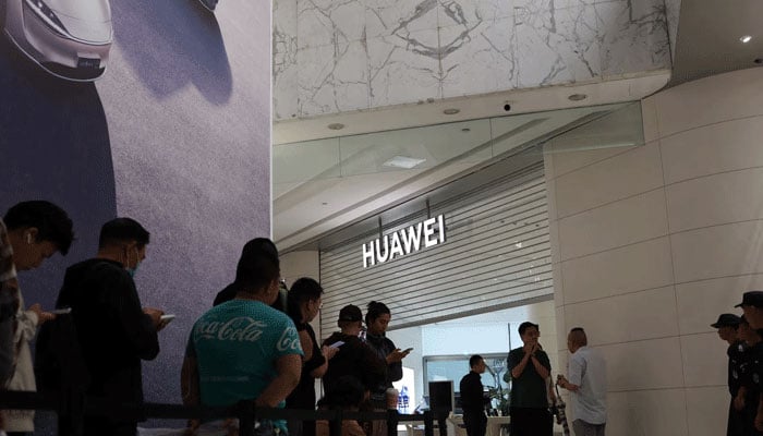 People queue outside a Huawei flagship store ahead of its opening hours, before the Huawei Mate XT tri-foldable smartphone goes on sale in Beijing, China  on September 20, 2024. — Reuters