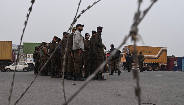 Police personnel stand guard along a road before a protest by supporters of former Prime Minister Imran Khans Pakistan Tehreek-e-Insaf (PTI) party for Khans release in Lahore on November 24, 2024. — AFP